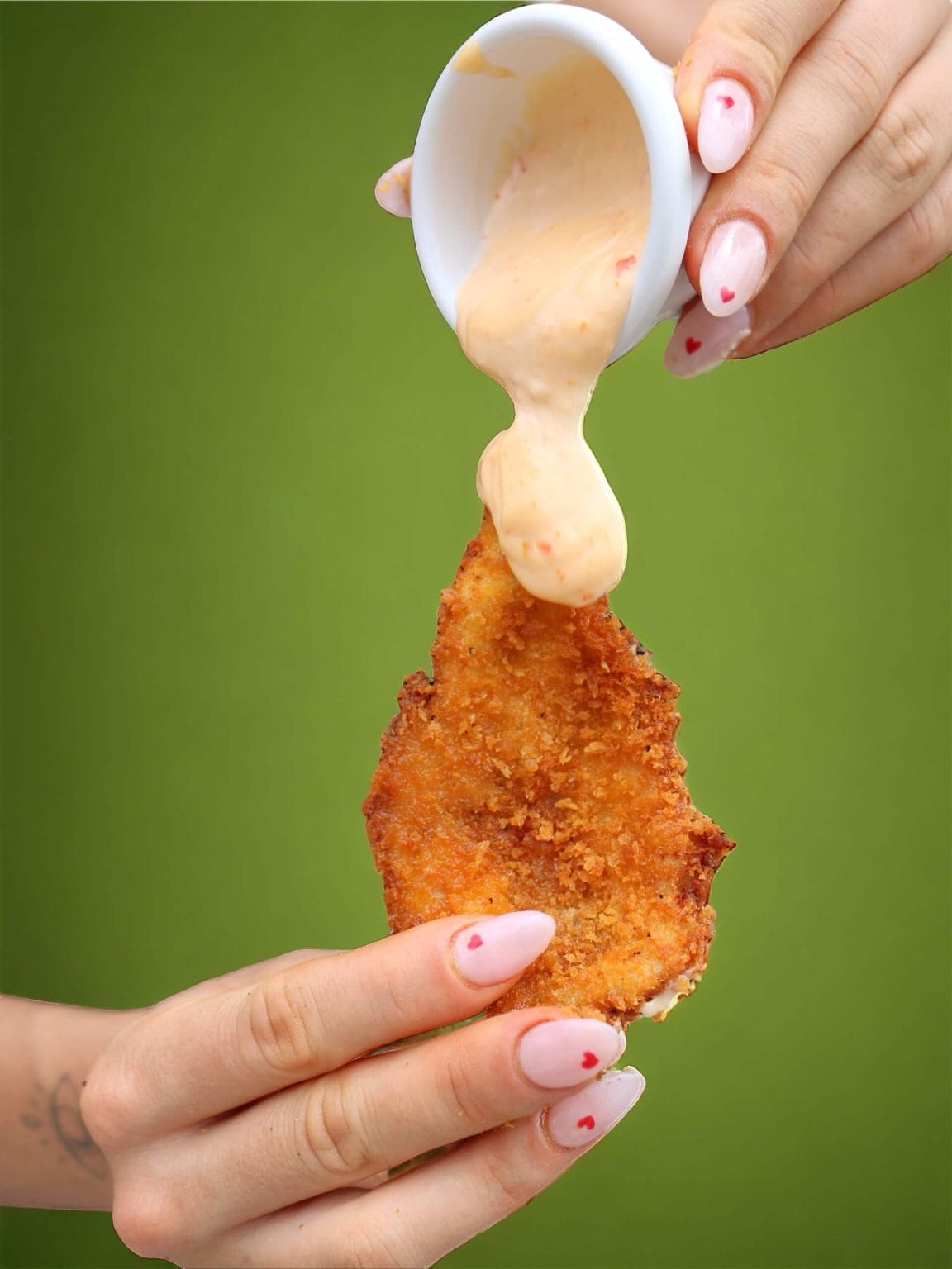 Aioli poured over a crumbed schnitzel